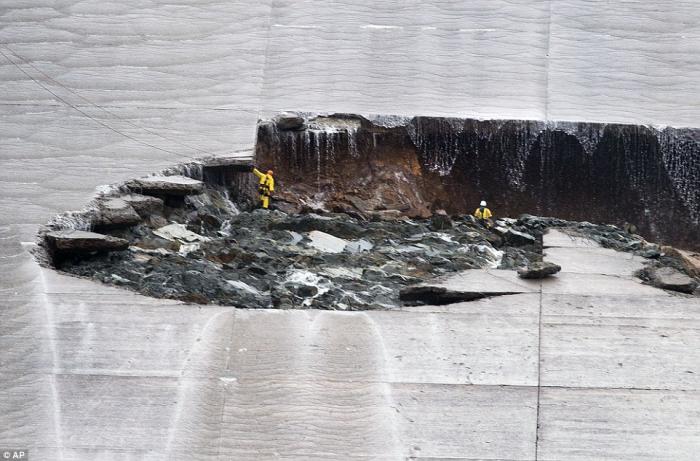 A close up provides a sense of scale. The hole in the spillway is simply massive.