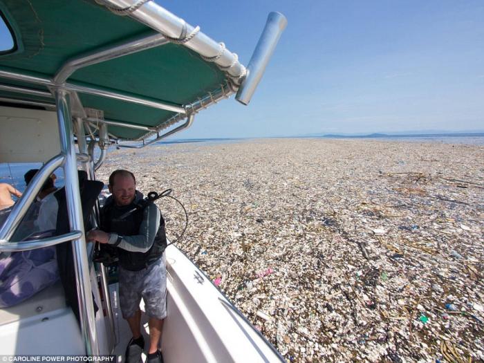 A diver looks with concern at the patch of plastic surrounding his boat. Imagine planning a vacation getaway only to see it turn into a dump. 