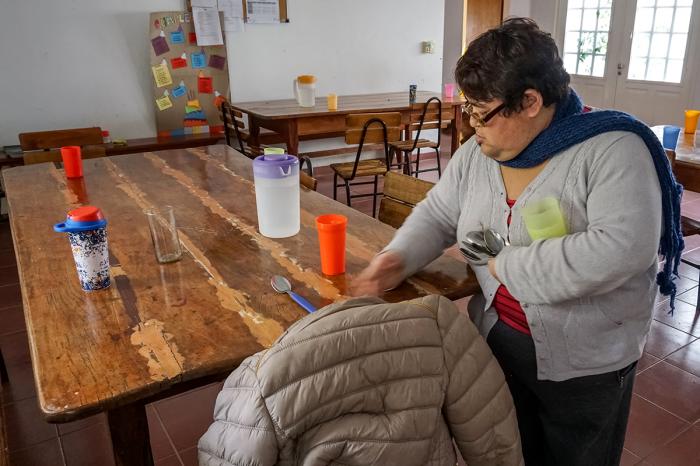 Sandra Cardozo, a regular at Fundacion IPNAâ s Centro de Dia, sets the table before a meal in the centerâ s dining hall.
